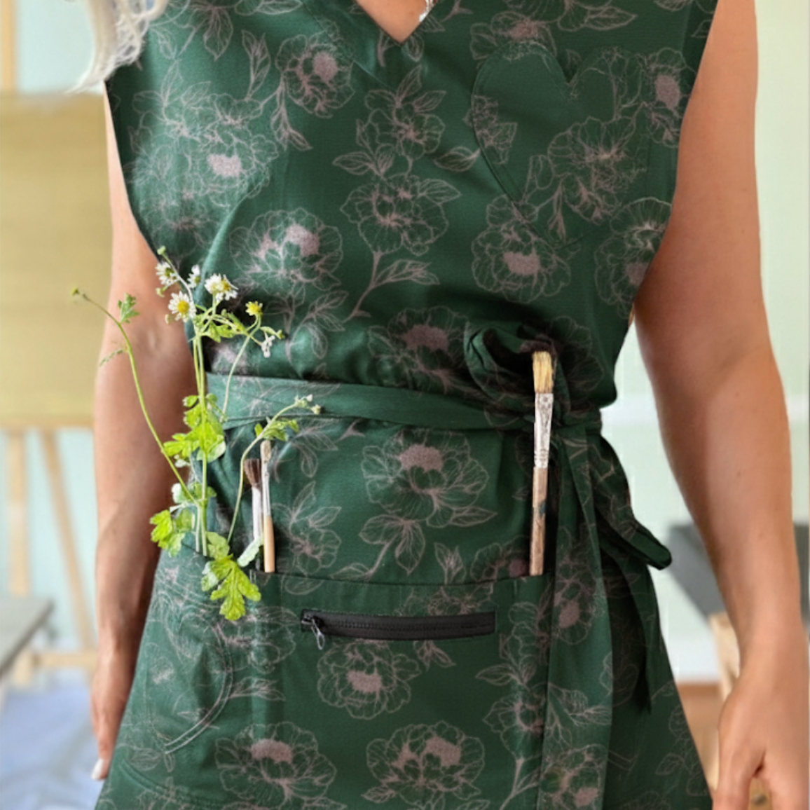 person wearing a green floral apron with pocket storage