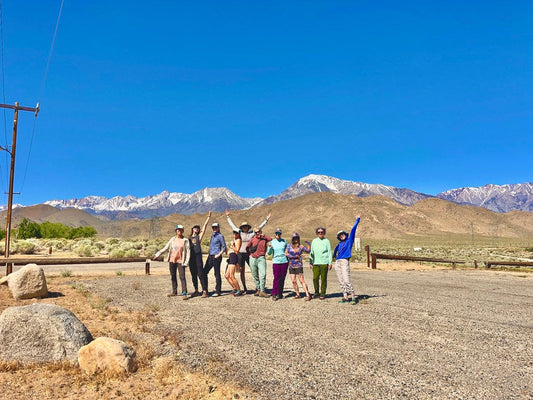 Group of women celebrating after rock climbing in Bishop, California, with the Sierra Nevada behind them.