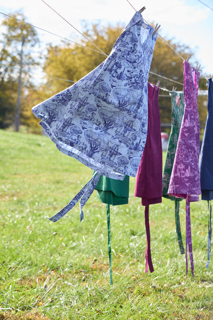Dresses hanging on a clothesline in an outdoor setting with grass and trees.