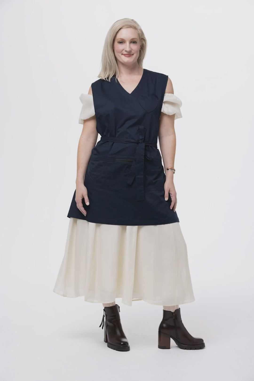 woman in a navy apron turning to face the back and show the back of the full coverage apron 